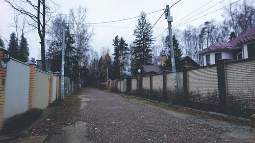 Road amidst trees and buildings against sky