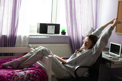 A teenage girl drags herself along while reading her school reading.