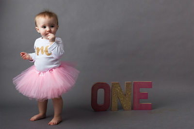 Baby girl standing with sparkling text over gray background