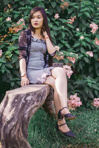 Young woman sitting against plants 