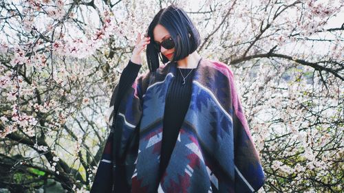 Portrait of woman wearing poncho against tree