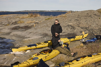 Men sitting near kayaks on rocky coast