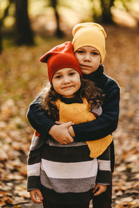 Happy cheerful children in warm clothes have fun walking running in autumn park playing with leaves