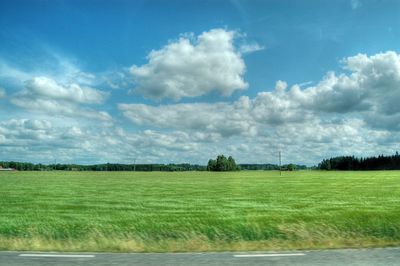 Scenic view of grassy field against cloudy sky