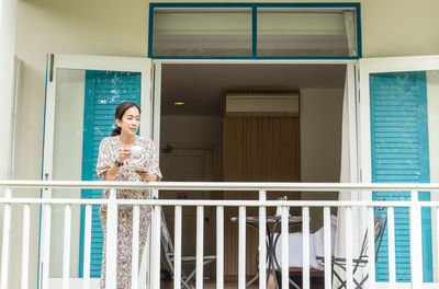 Portrait of woman standing against window