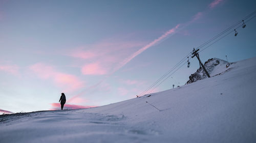 Low angle view of woman walking on snowcapped mountain against sky