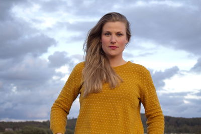 Portrait of beautiful young woman standing against sky