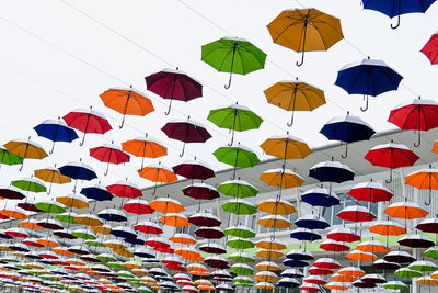 Low angle view of multi colored umbrellas hanging against sky