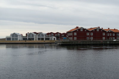 Residential buildings by river against sky