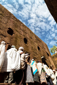 Low angle view of people standing by old building 