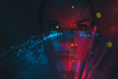 Close-up portrait of young woman by illuminate lights