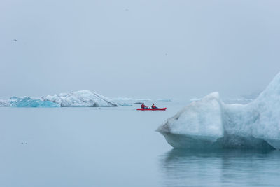 Man paddling in a kayak in the freezing waters of jokulsarlon glacier lagoon between icebergs