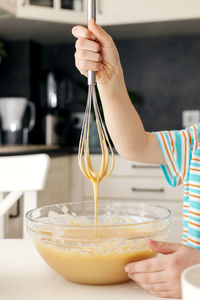 Close-up of a whisk with dough. the boy is kneading the dough for a pie or a cookie. the dough