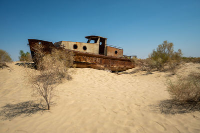 Abandoned building on beach against clear blue sky