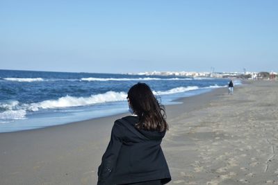 Rear view of woman on beach against sky