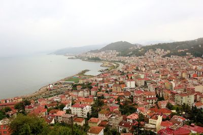 High angle view of townscape by sea against sky