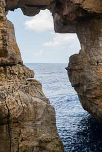 Rock formation by sea against sky