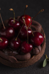 Cake with cherry and chocolate cream on a black plate