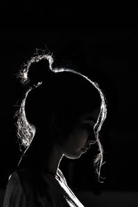 Portrait of young woman against black background