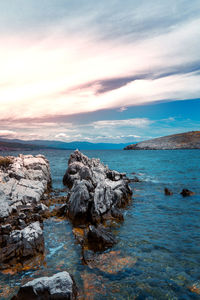 Rocks on sea shore against sky during sunset