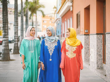 Happy female friends walking by building