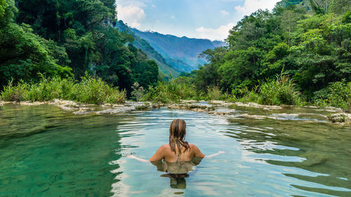 Rear view of woman swimming in river