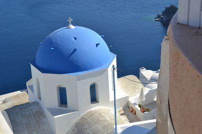 High angle view of a white church with a blue dome near the sea in santorini, greece