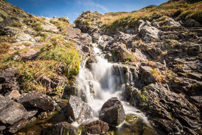 Low angle view of waterfall against sky