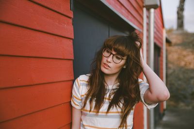 Portrait of beautiful young woman standing against brick wall