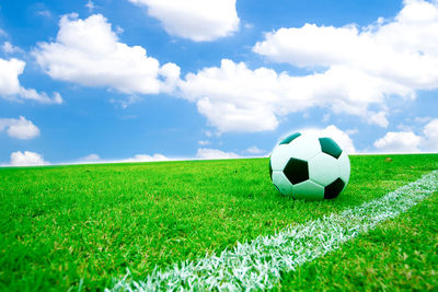 Soccer ball on field against cloudy sky