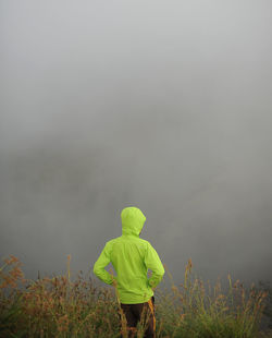 Rear view of man walking on field against sky