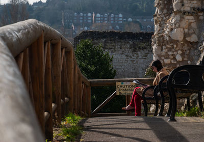 Rear view of people sitting by buildings in city