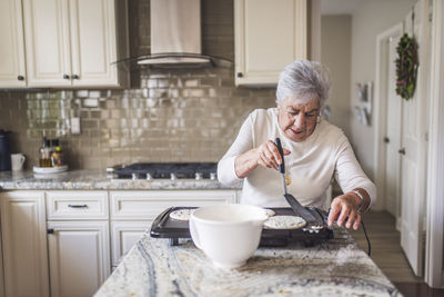 Portrait of senior woman cooking pancakes for breakfast