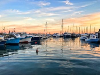 Sailboats moored on sea against sky during sunset