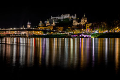 Illuminated light reflecting on river against sky at night