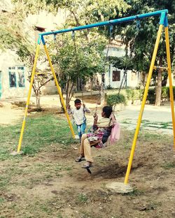 Children playing on swing in playground
