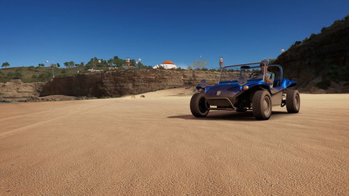 Cars on road by land against clear blue sky