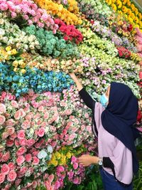 Low section of woman holding bouquet of flowering plant