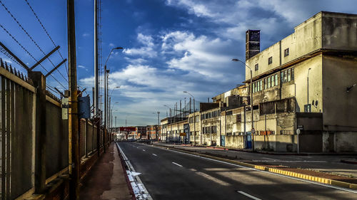 Road by buildings against sky in city