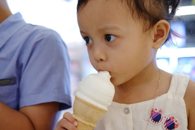 Cute girl eating ice cream at shop