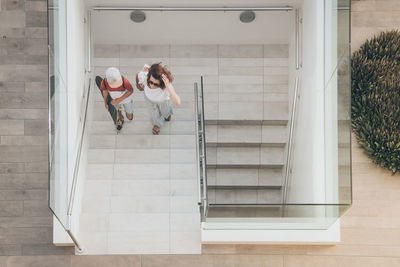 High angle view of mother and son walking on staircase