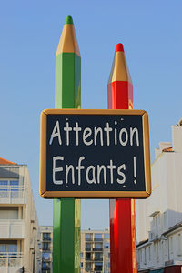 Low angle view of road sign against clear blue sky