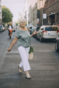 Full length portrait of woman walking on sidewalk in city