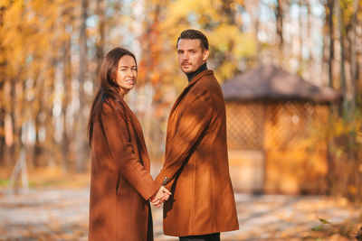 Portrait of couple standing by tree during autumn