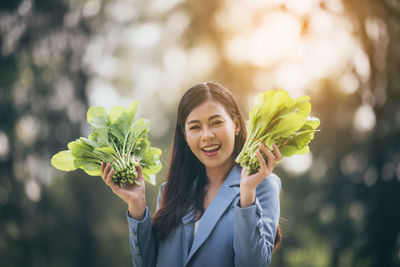 Portrait of woman holding flowering plant