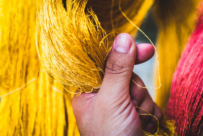 Close-up of hand holding yellow threads