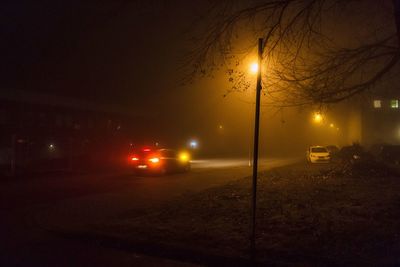 Cars on illuminated street against sky at night