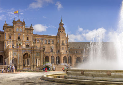 Plaza de espana at sevilla, spain. view of fountain in foreground in city against sky