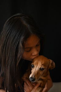 A girl with dog against black background