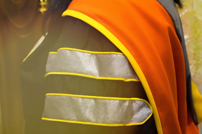 Midsection of woman wearing graduation gown